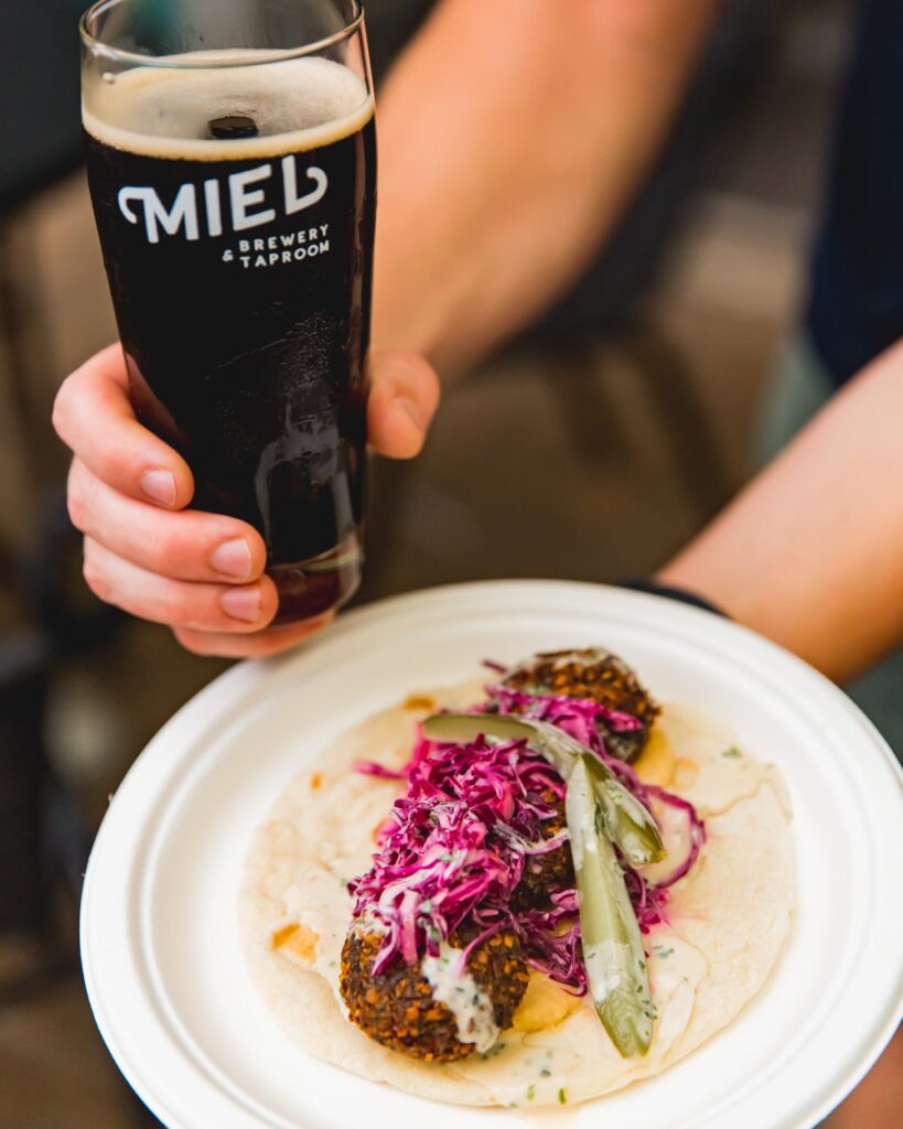 A plate of hummus and falafel and a glass of Miel Beer