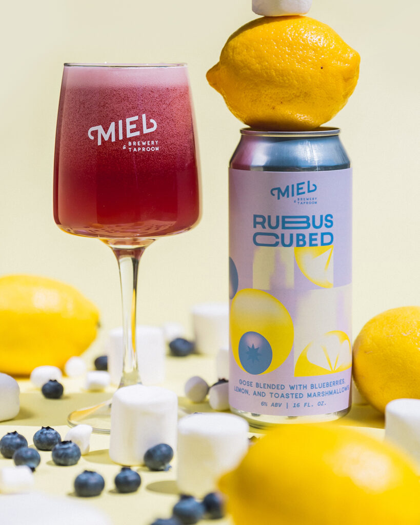 a stemmed glass of Rubus Cubed sour next to a can